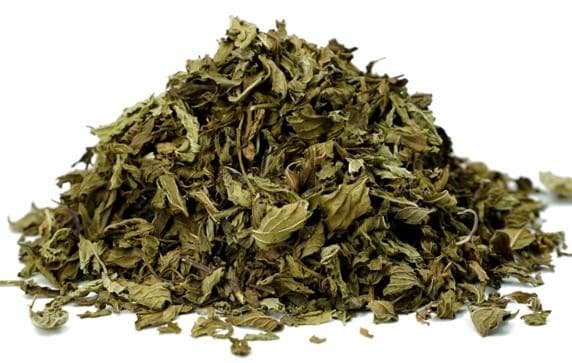 Pile of dried spearmint leaves on a white background