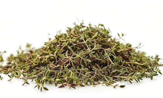 Pile of dried thyme leaves on a white background